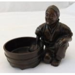 An oriental bronze of a washer woman kneeling by her bowl, 7cm (dia)