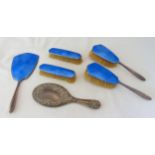 A five piece hallmarked silver and enamel dressing table set to include a hand mirror, clothes and