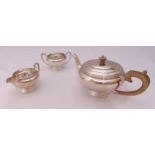 A hallmarked silver three piece tea set, compressed cylindrical with scroll handles on raised