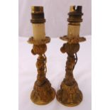 A pair of late 19th century brass candlesticks in the form of stylised dolphins on raised circular