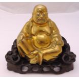 A seated brass smiling Buddha on pierced and carved hardwood stand, 18 x 21cm