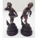 A pair of spelter figurines of a boy and girl on raised circular bases, 23cm (h)