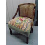 An early 20th century tub chair with tapestry seat and caned back