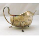 A hallmarked silver sauce boat with scroll handle on three scroll legs, Sheffield 1938 by Edward