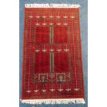 A Middle Eastern wool red ground carpet with repeating geometric patterns, 165 x 94.5cm