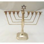 A hallmarked silver Menorah, with angled arms, panelled oval stem on raised square base,