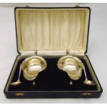 A cased set of hallmarked silver sauce boats and ladles, cut edge, loop handle on three scroll legs,