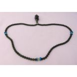 A jade bead necklace with a carved stylised Dog of Foe pendant
