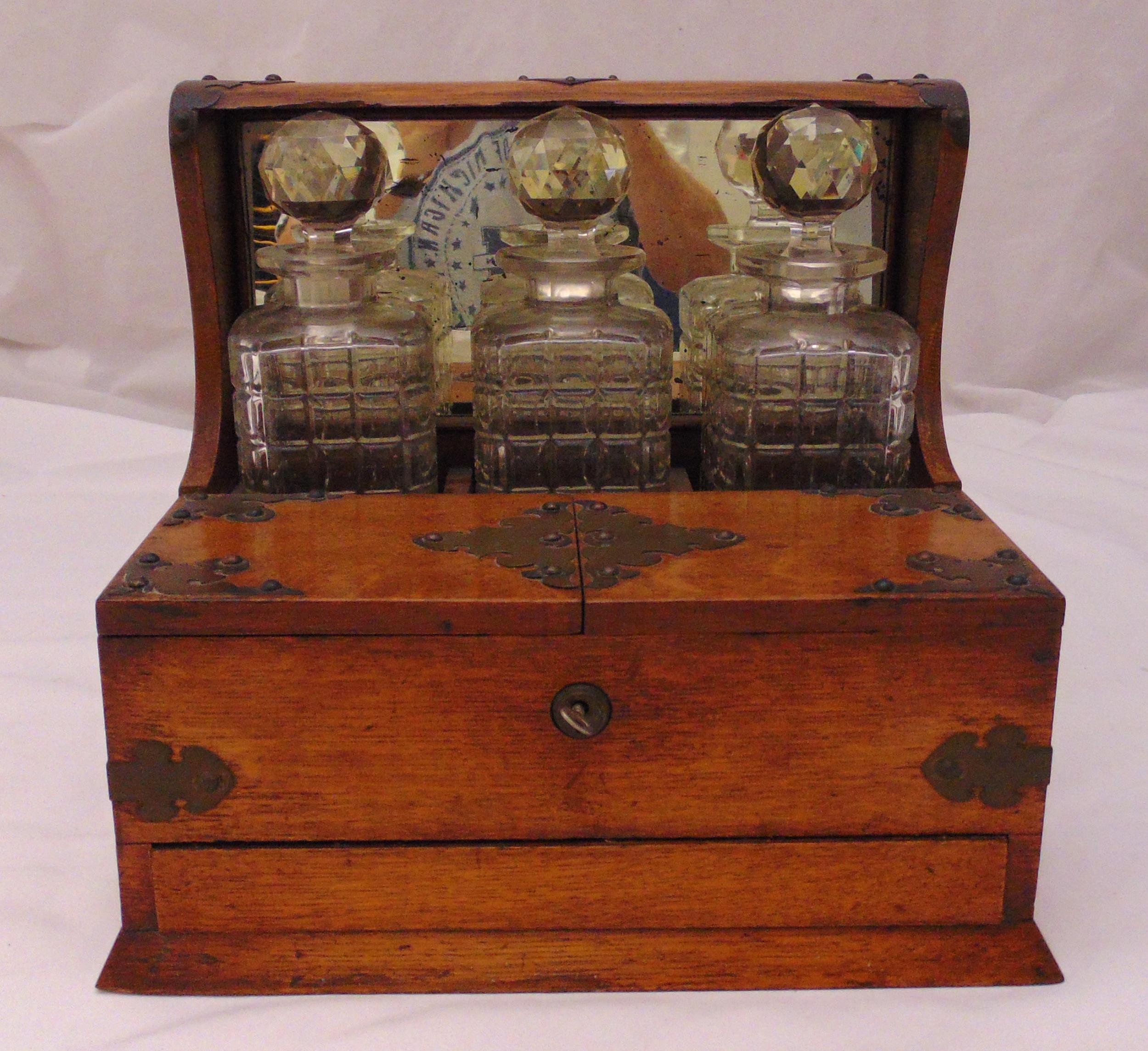 An oak Tantalus with three decanters, one decanter A/F, 31 x 35 x 26.5cm