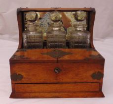 An oak Tantalus with three decanters, one decanter A/F, 31 x 35 x 26.5cm