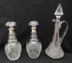 A pair of cut glass crystal decanters with hallmarked silver collars and a cut glass claret jug with