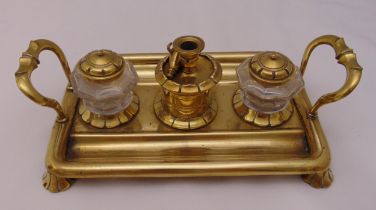 A brass two handled rectangular desk stand with two glass inkwells, a taper stick holder and a