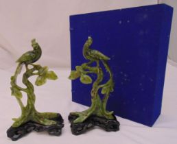 A pair of jadeite carved stylised birds seated on branches mounted on hardwood stands to include