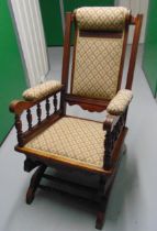 An oak upholstered rocking chair with turned sides