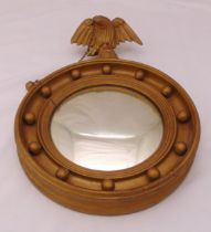 A Regency style circular gilded wooden wall mirror with eagle finial, 47 x 29.5cm