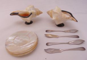 A pair of conch shell salts mounted on silver stands, a set of four mother of pearl butter dishes