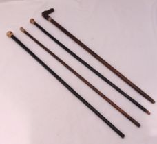 Three antique walking canes with hallmarked silver handles and a carved wooden handled walking