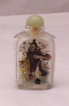 A Chinese reverse painted snuff bottle decorated with figures and a tiger