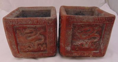 A pair of oriental red stone ceramic plant holders of square form with Chinese dragon motifs in