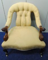 A Victorian upholstered mahogany armchair with carved legs on original castors