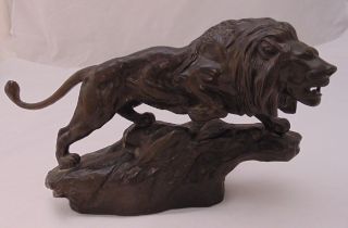 A resin figurine of a lion on naturalistic base, 18 x 30cm