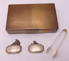 A hallmarked silver engine turned cigarette box, two hallmarked silver bottle labels and a