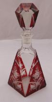 An Art Deco overlaid ruby glass decanter of geometric form etched with flowers and leaves and drop