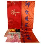 A boxed Oriental red silk wall hanging, with embroidered script and fringe, 73cm across, and a box