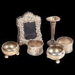 A pair of silver napkin rings, a pair of small silver salts, a small silver-fronted frame, and small