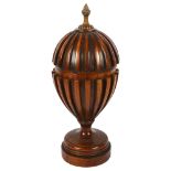 A carved mahogany urn and cover, with fluted design and brass finial, 36cm