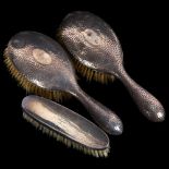 A pair of hammered silver-backed clothes brushes, and another