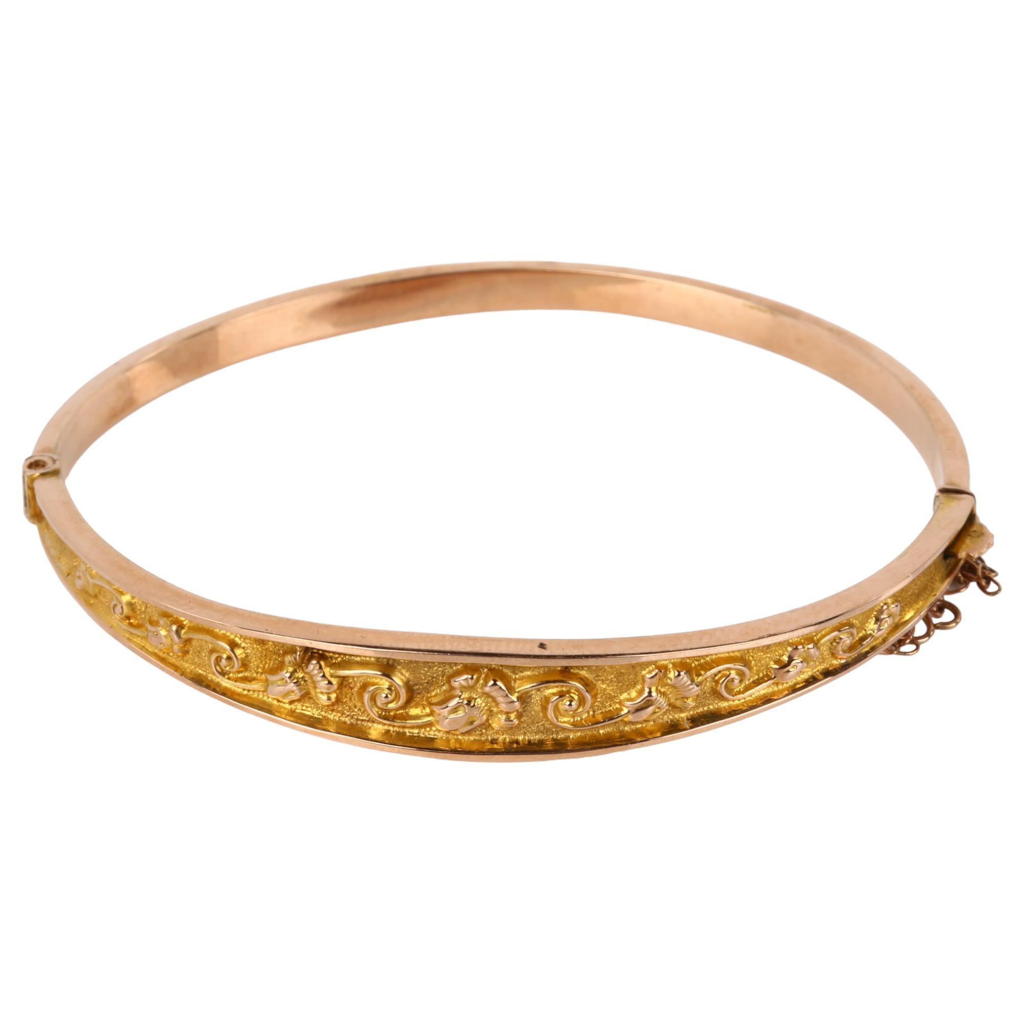 An early 20th century 9ct gold hinged bangle, relief embossed foliate decoration, maker's marks S