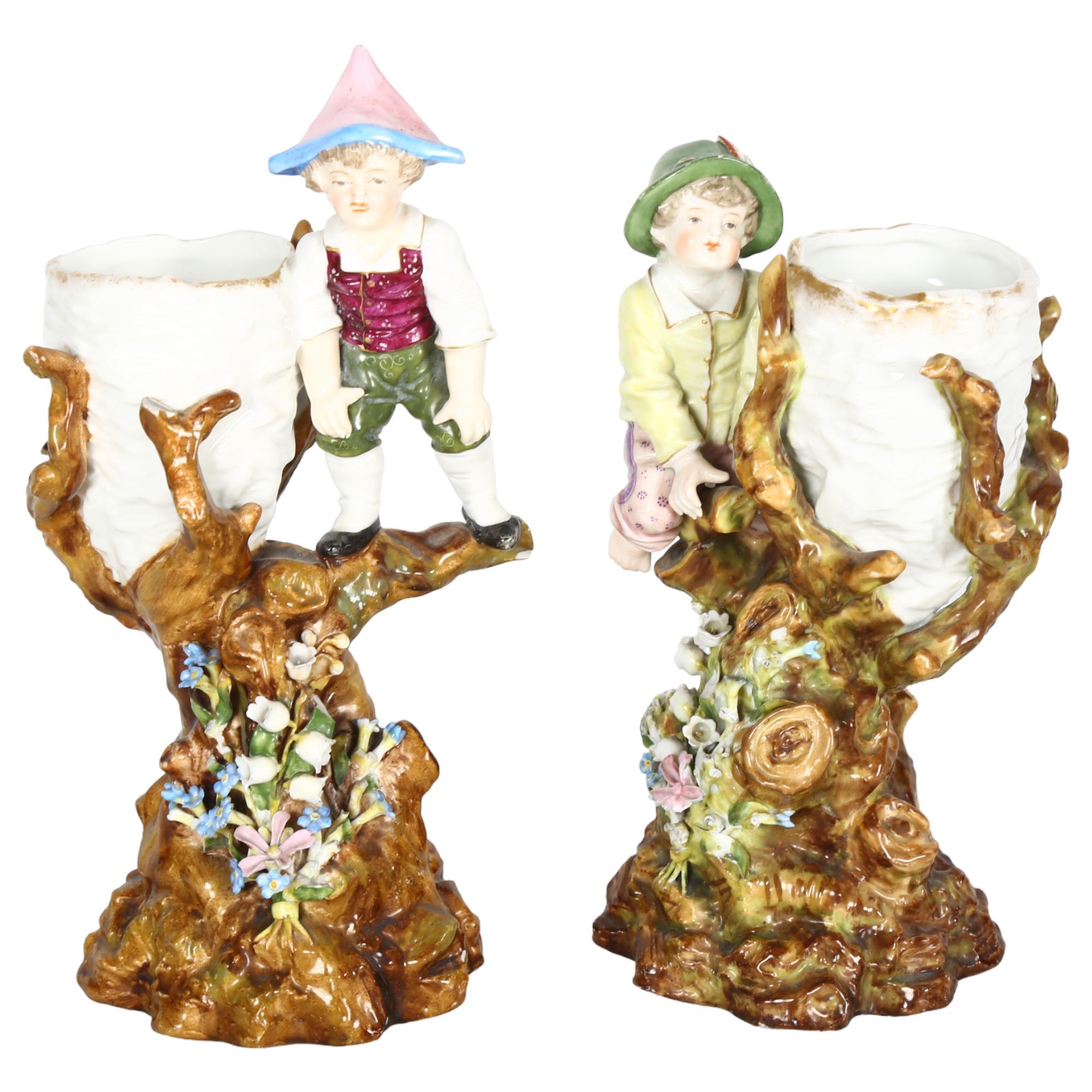 A pair of Vintage German porcelain vases, surmounted by boy figures on flower strewn bases,