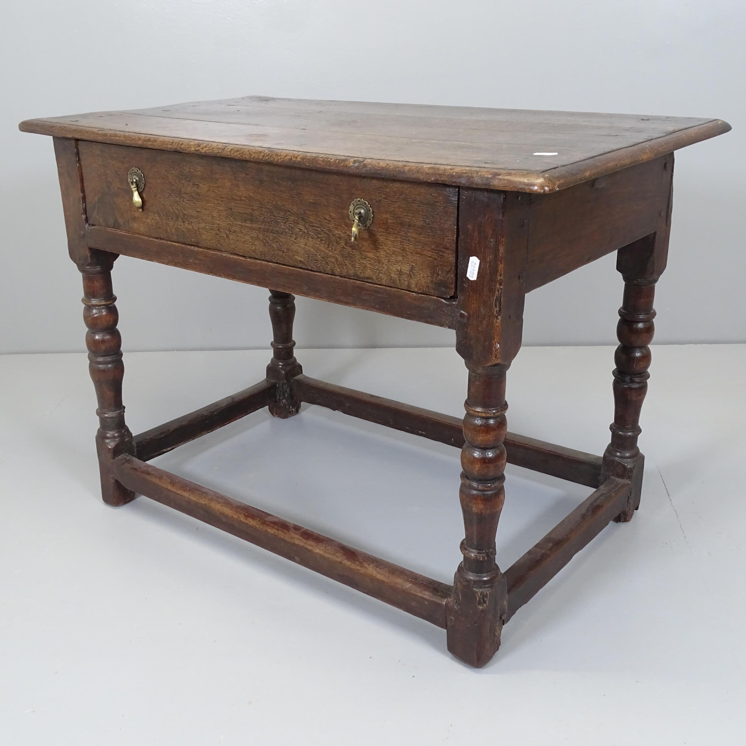 An 18th century oak side table with single frieze drawer, raised on turned legs with all around