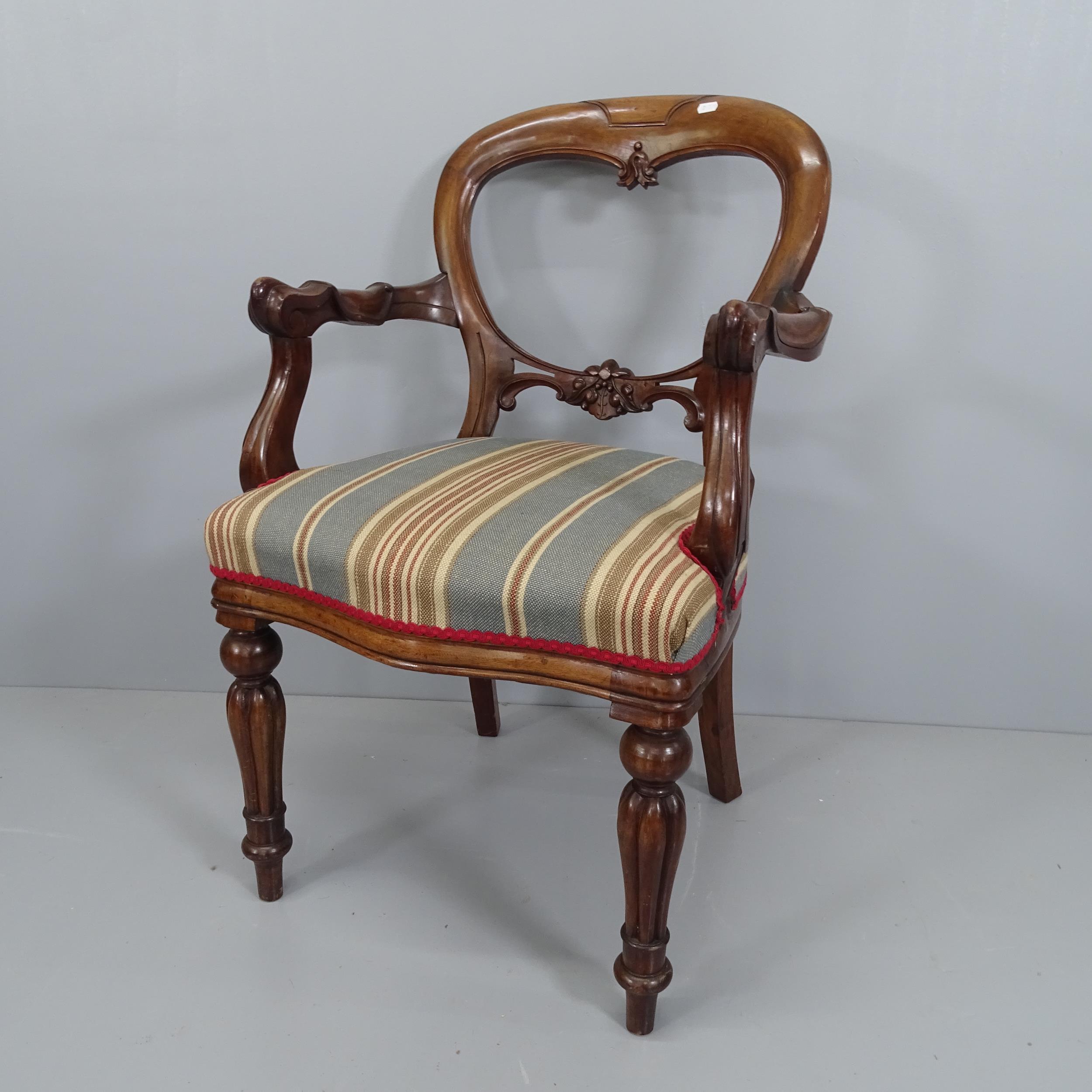 A 19th century mahogany open arm chair, with balloon back and carved decoration.