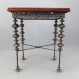 An unusual design side or lamp table, with the mahogany top on ornate base with beaten metal