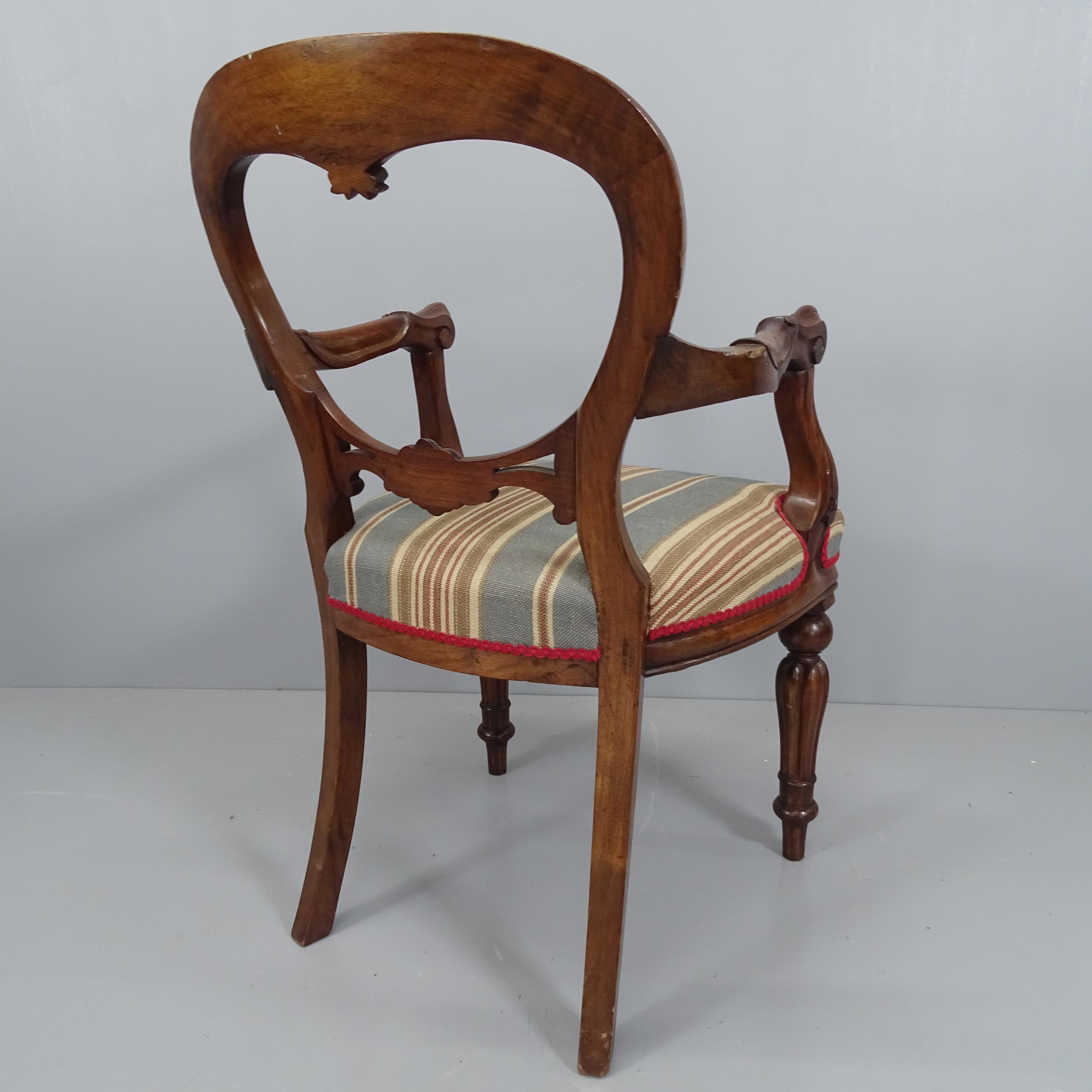 A 19th century mahogany open arm chair, with balloon back and carved decoration. - Image 2 of 2