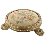 A Georgian tapestry-topped footstool, with gilded wood surround and lion paw feet, diameter approx