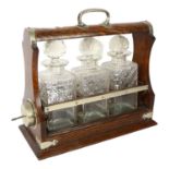 A silver plated oak tantalus, with 3 cut-glass decanters and stoppers, L33.5cm