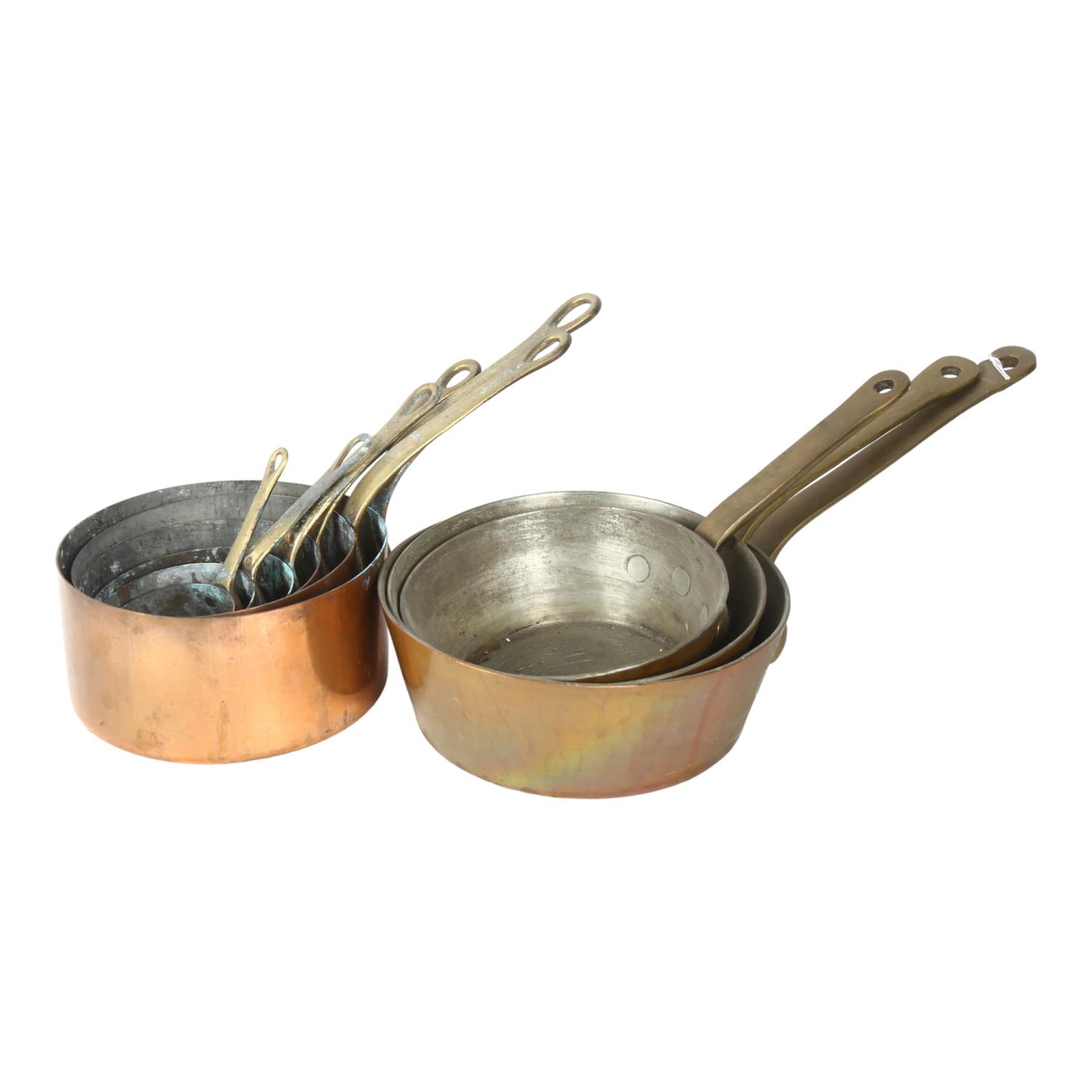 A graduated set of 3 copper pans with brass handles, largest 20cm diameter, and a set of 6 copper