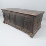 An 18th century panelled oak coffer with carved decoration. 132x55x64cm. Various marks and