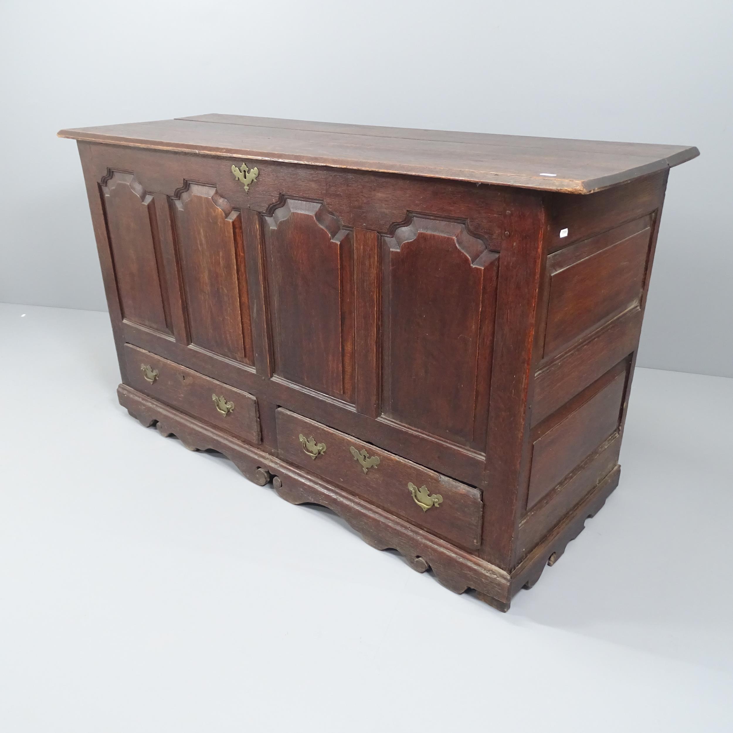 An antique panelled oak mule chest, with brass mounts. 152x88x60cm