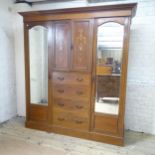 An Edwardian mahogany triple compactum wardrobe in five sections, with two mirrored doors, cupboards