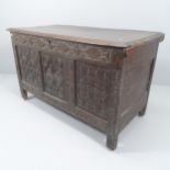 An antique carved oak coffer, raised on stile legs. 122x74x58cm.