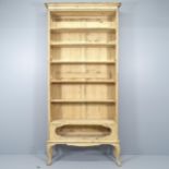 An antique pine two-section open bookcase, with five fixed shelves and raised on cabriole legs.