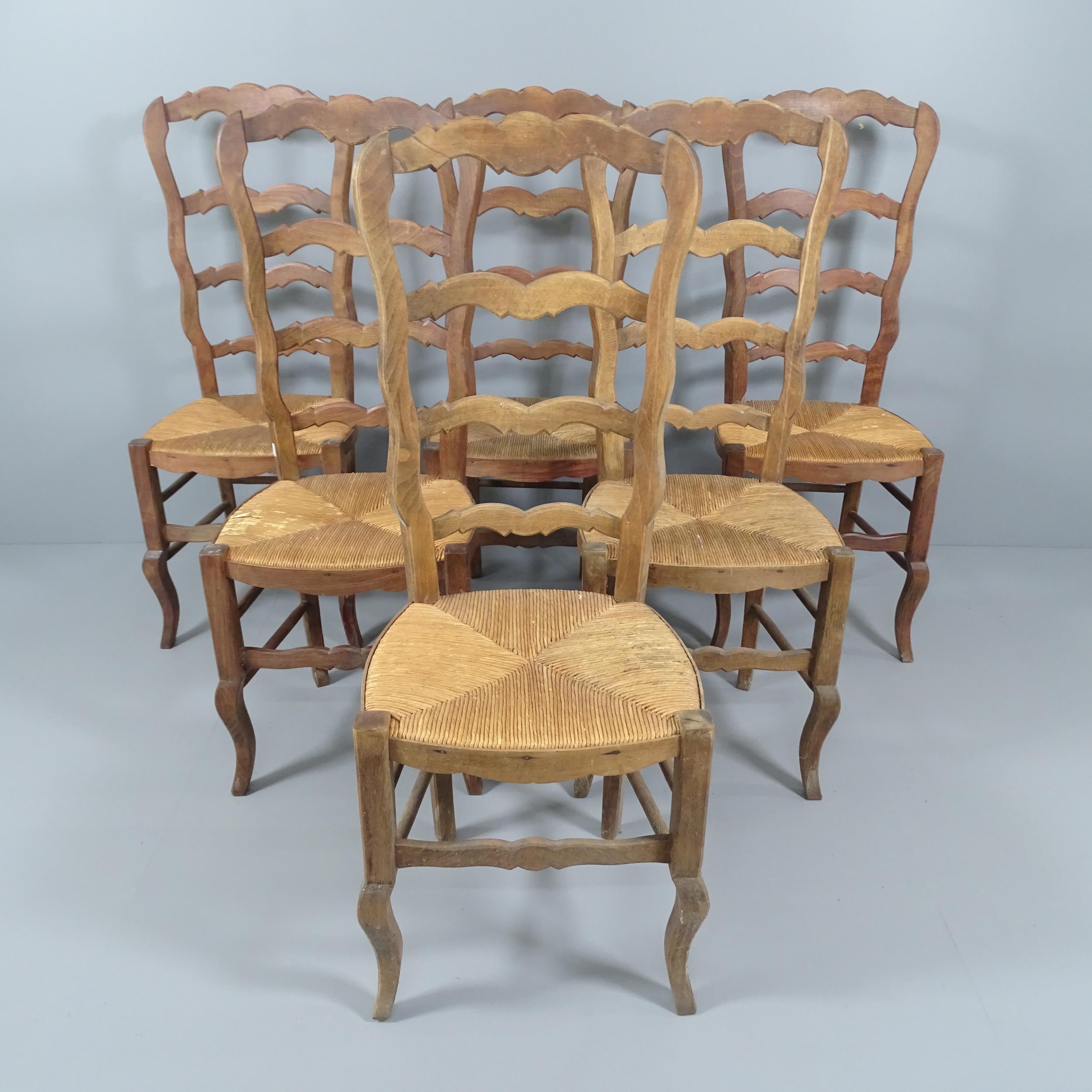 A set of six French oak ladderback dining chairs. One has visible repair to back rail. Some moisture