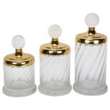 A graduated set of 3 Hollywood Regency style glass cylinder jars, with gilded metal lid and