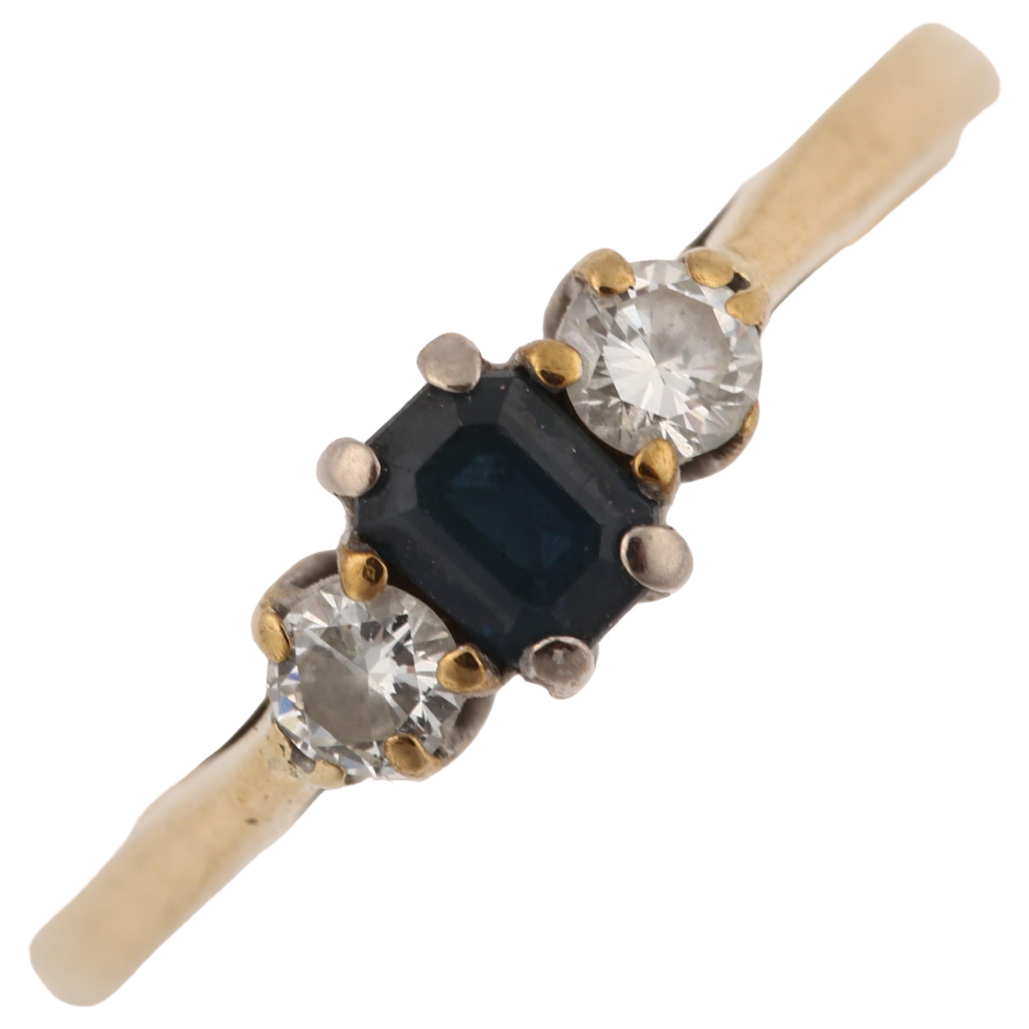 A modern 9ct gold three stone sapphire and diamond ring, set with emerald-cut sapphire and modern