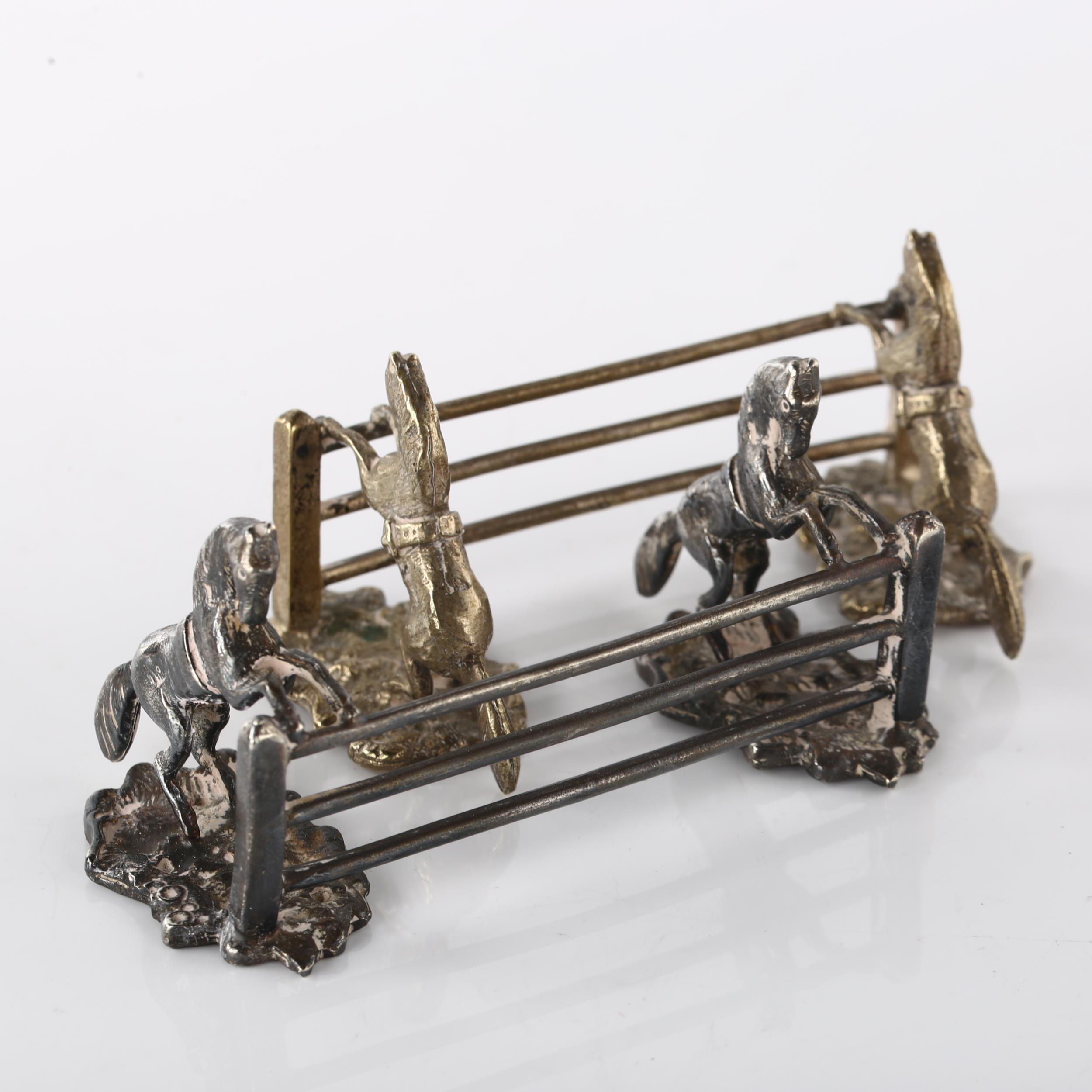 A pair of Antique silver plated novelty horse racing knife rests, modelled as horses jumping fences, - Image 3 of 3