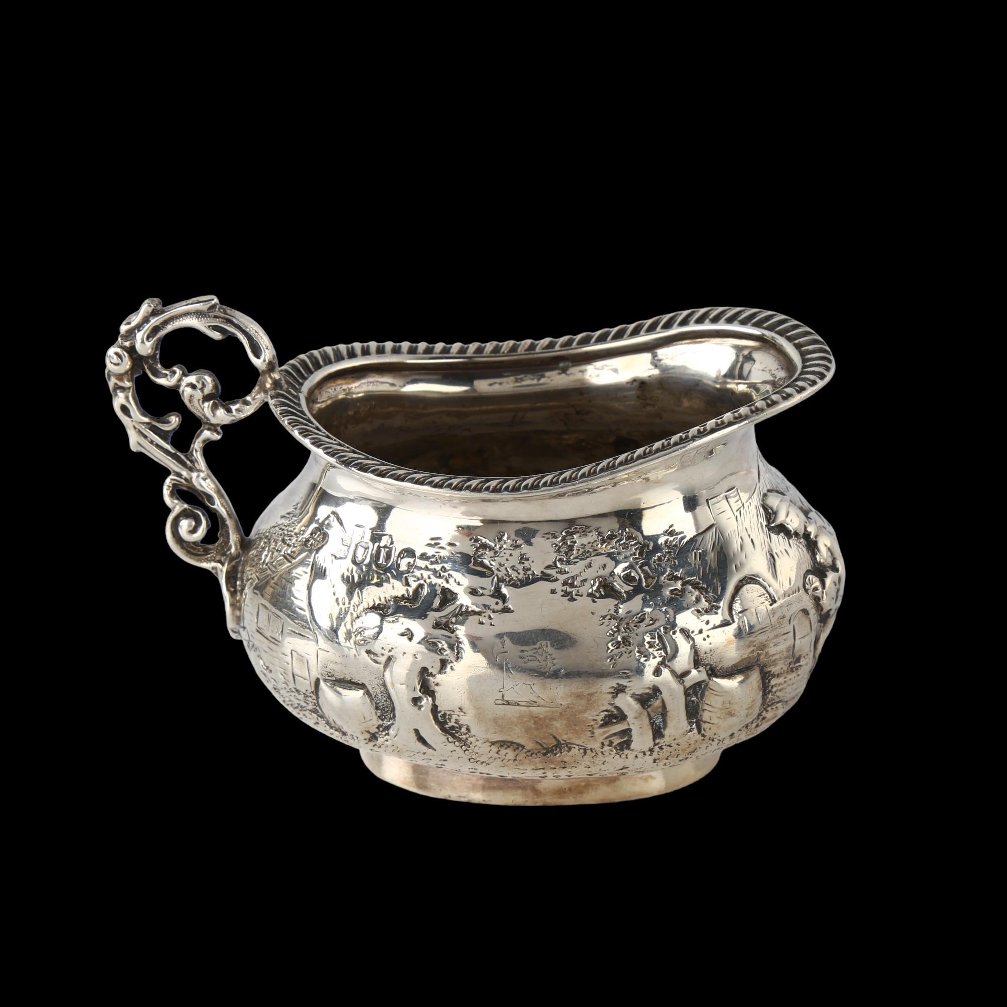 A Victorian silver cream jug, oval bulbous form with relief embossed village decoration and